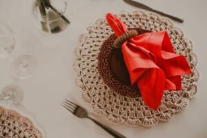 From above arrangement of fancy banquet set with red napkin in holder on brown ceramic plate