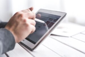 Close-up of a hand using a stylus on a tablet, showcasing digital technology interaction.