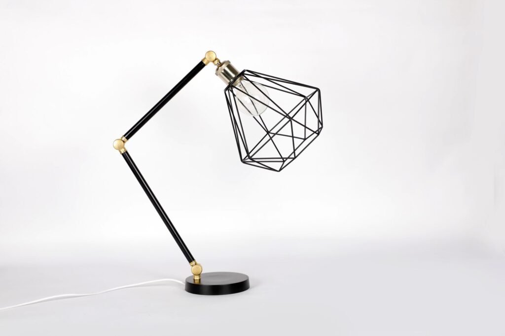 Minimalist geometric metal table lamp with adjustable design on a white backdrop.
