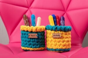 Vibrant handmade pen holders with markers on a stylish pink chair.