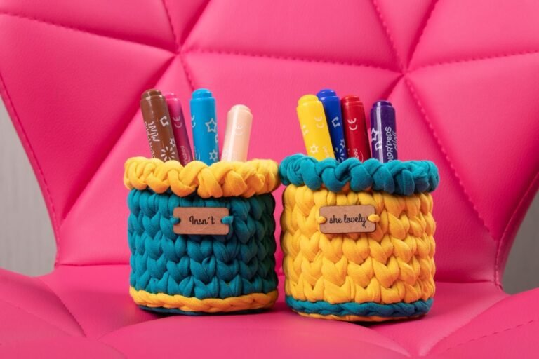 Vibrant handmade pen holders with markers on a stylish pink chair.