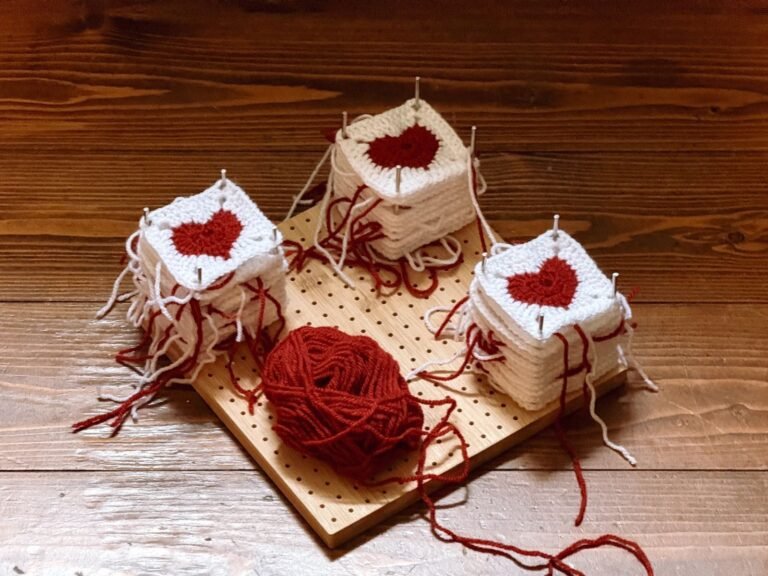 A creative display of red heart crochet squares on a wooden board with yarn, perfect for DIY projects.